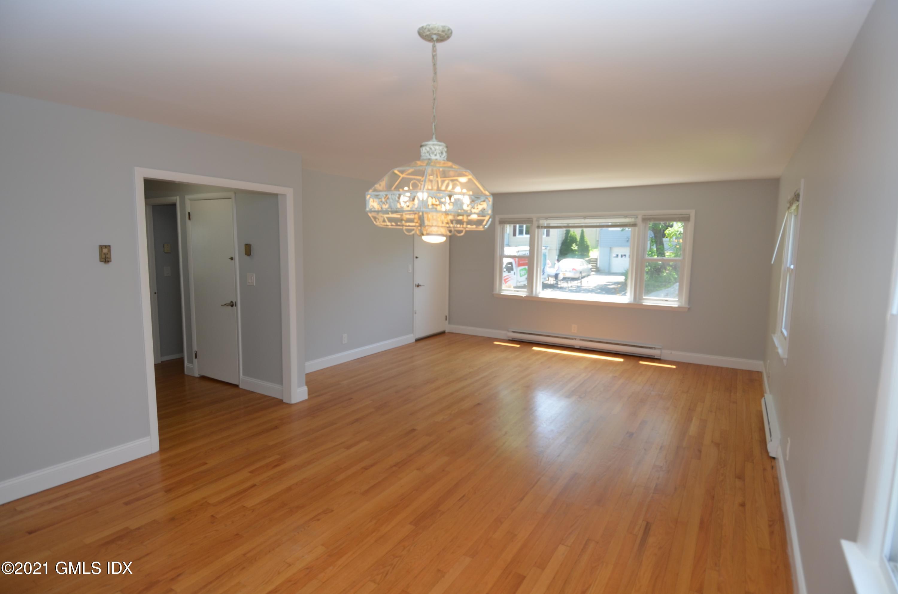 5 Ridge Place, Unit 1 Greenwich, CT 06831 - Photo 6 of 29 an empty room with wooden floor chandelier and windows
