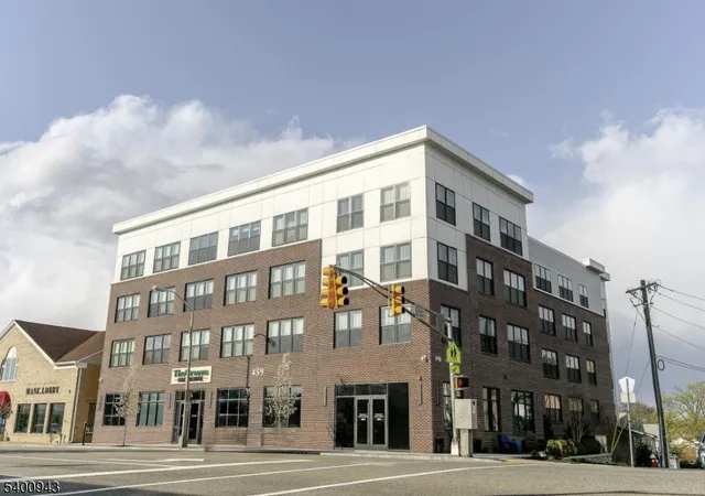 a front view of a building with lot of cars and trees