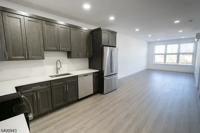 a kitchen with stainless steel appliances granite countertop a refrigerator a sink dishwasher and wooden cabinets with wooden floor