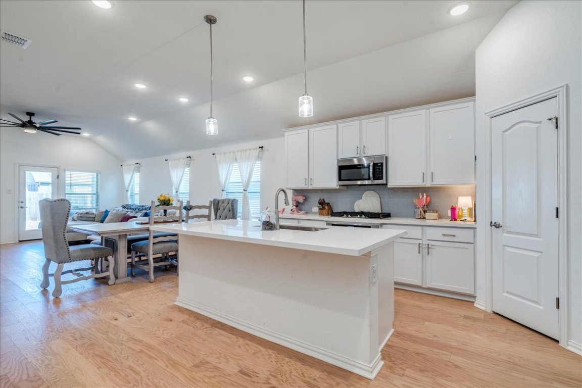 409 Durian Loop Buda, TX 78610 - Photo 29 of 30 Kitchen with vaulted ceiling, decorative light fixtures, white cabinetry, a kitchen island with sink, and open floor plan