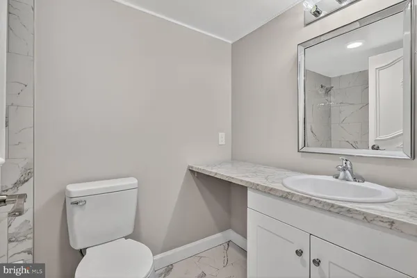 a bathroom with a granite countertop toilet sink and mirror