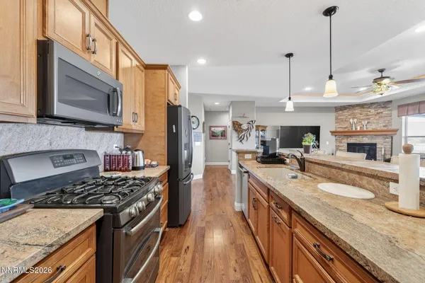 a kitchen with stainless steel appliances granite countertop a sink a stove and a wooden floors