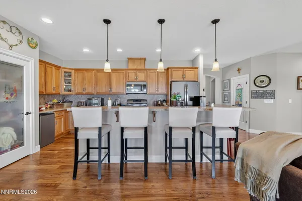 a kitchen with stainless steel appliances kitchen island granite countertop a table chairs and a view of living room