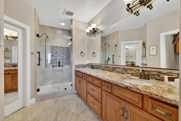 a bathroom with a granite countertop double vanity sink mirror shower and double