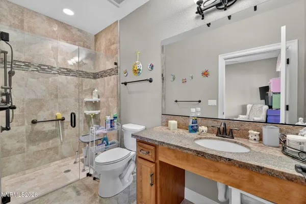 a bathroom with a granite countertop sink toilet a mirror and shower