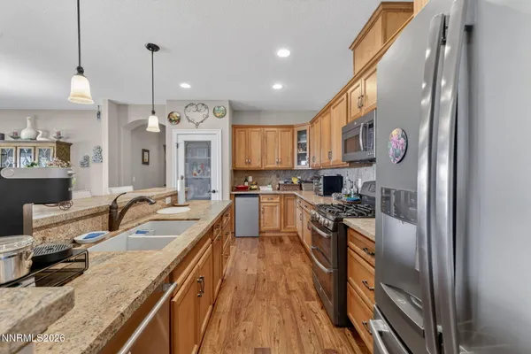a large kitchen with stainless steel appliances granite countertop a sink a stove and a refrigerator