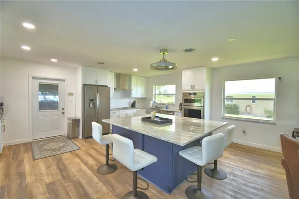 a dining hall with stainless steel appliances a dining table and chairs with wooden floor