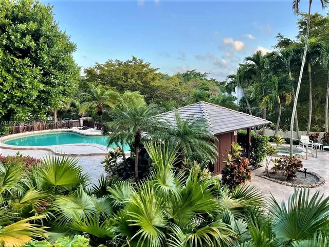 a view of a patio with table and chairs potted plants and large tree