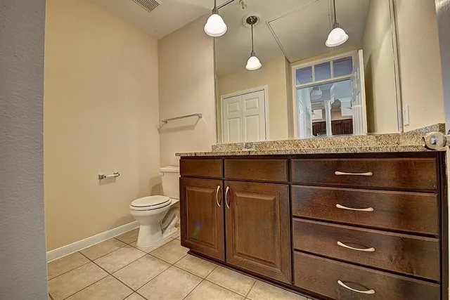 a bathroom with a granite countertop toilet sink and mirror
