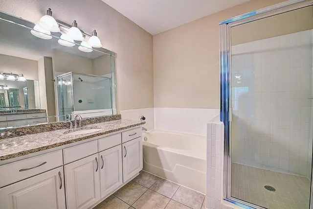 a bathroom with a granite countertop sink a mirror and a bathtub