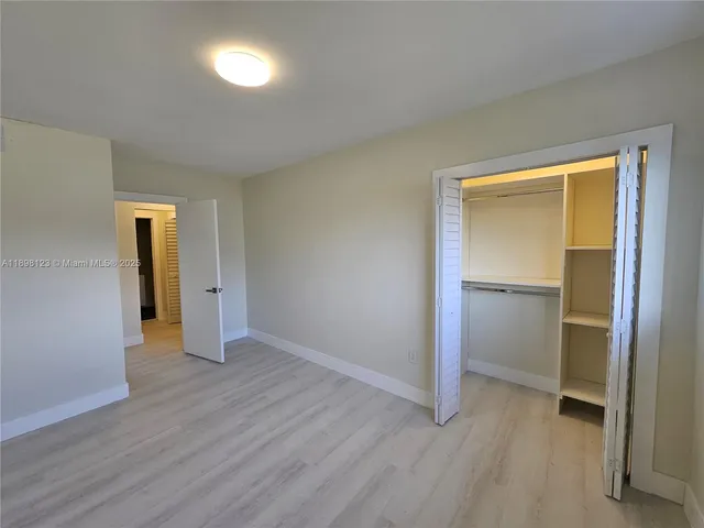 an empty room with large window and wooden floor