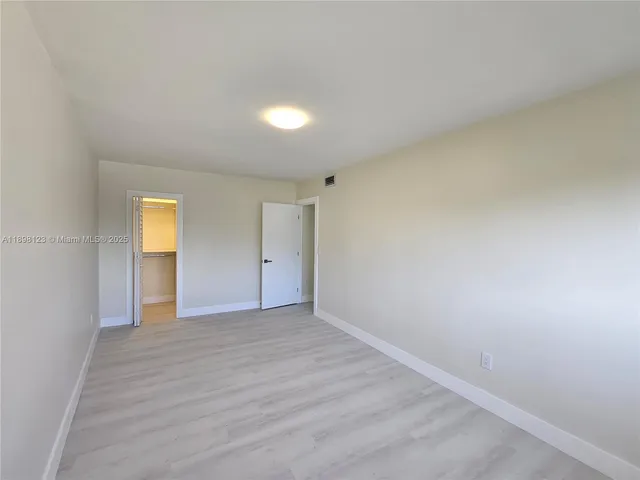 a view of an empty room with wooden floor and closet