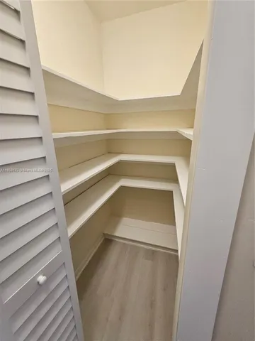 a view of an empty room with wooden floor and closet