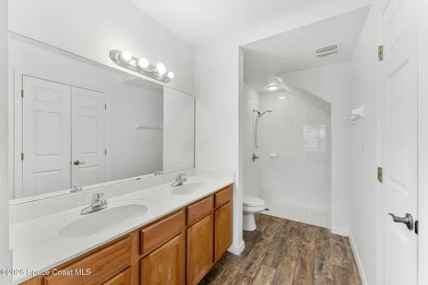 a bathroom with a double vanity sink a large mirror and shower