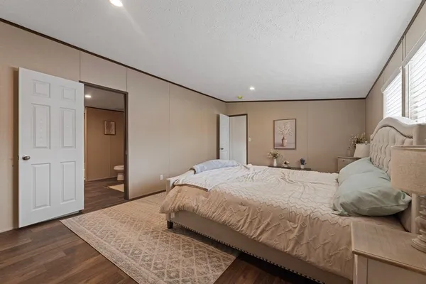 a bedroom with a large bed and wooden floor