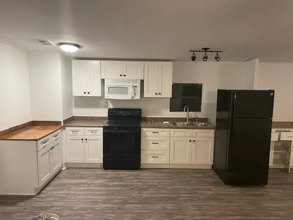 a kitchen with granite countertop a refrigerator stove top oven and cabinets