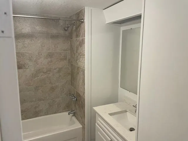 a bathroom with a tub shower sink vanity and a sink