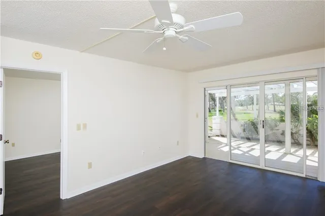 an empty room with wooden floor and fan