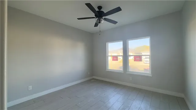 an empty room with a window and a ceiling fan