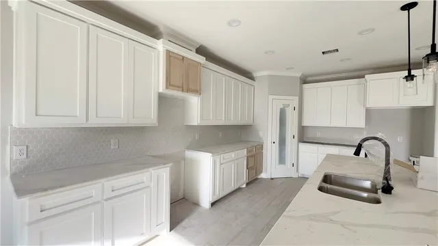 a kitchen with white cabinets and sink