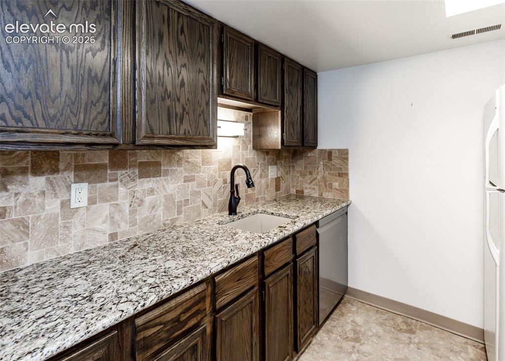 1034 Fontmore Road, Unit D Colorado Springs, CO 80904 - Photo 16 of 43 a kitchen with granite countertop wooden cabinets a sink and dishwasher