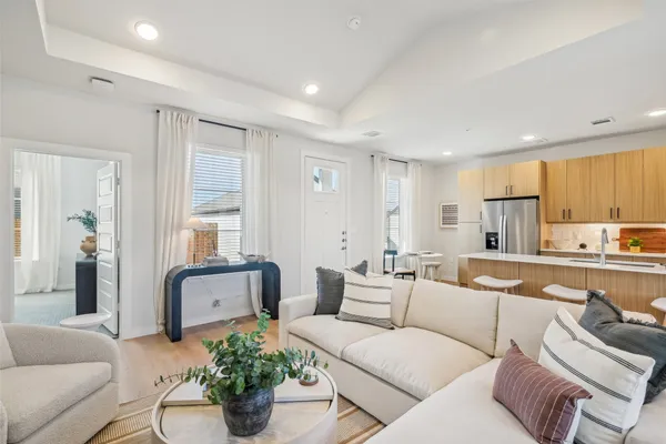 a living room with furniture white walls and kitchen view