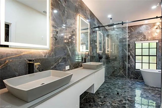 a bathroom with a tub a sink and a large mirror next to a window