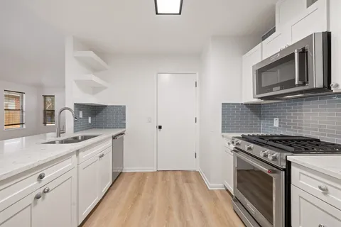 a kitchen with granite countertop a sink stove and microwave