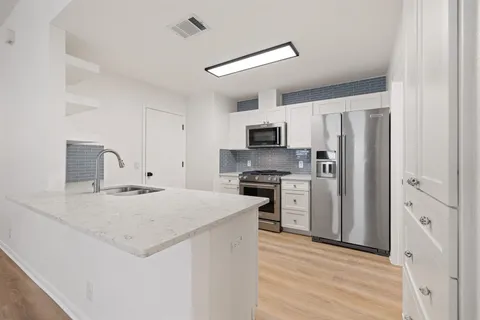a kitchen with a refrigerator a stove top oven a sink and dishwasher with wooden floor