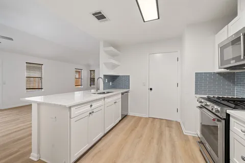 a kitchen with granite countertop a sink stove and cabinets