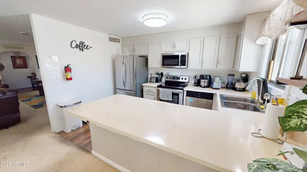 a kitchen with stainless steel appliances a white refrigerator a stove a sink a microwave and a refrigerator