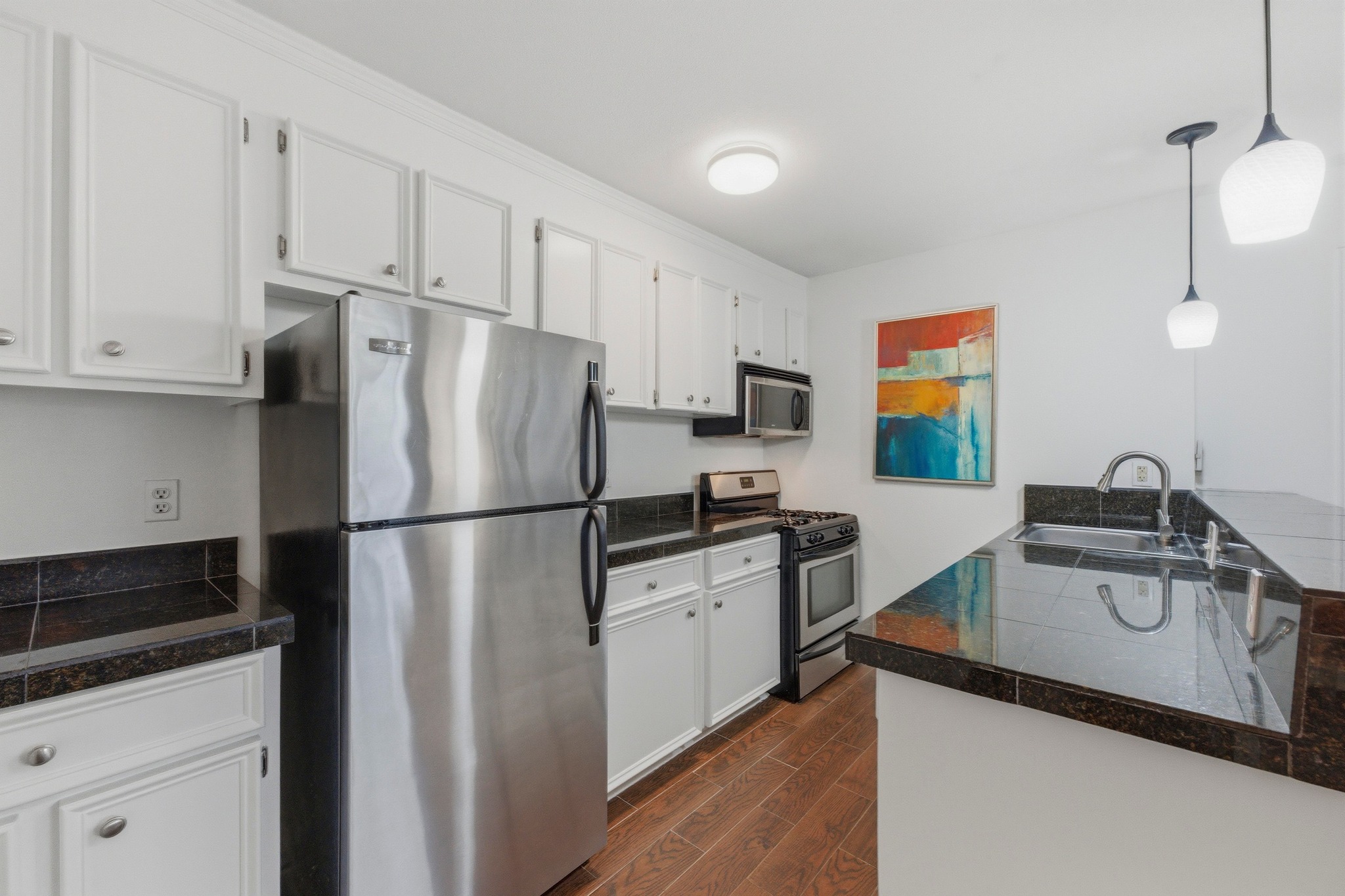 304 East 33rd Street, Unit 11 Austin, TX 78705 - Photo 7 of 27 a kitchen with stainless steel appliances a refrigerator sink and white cabinets