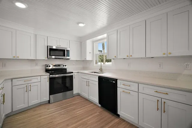 a kitchen with granite countertop white cabinets and stainless steel appliances