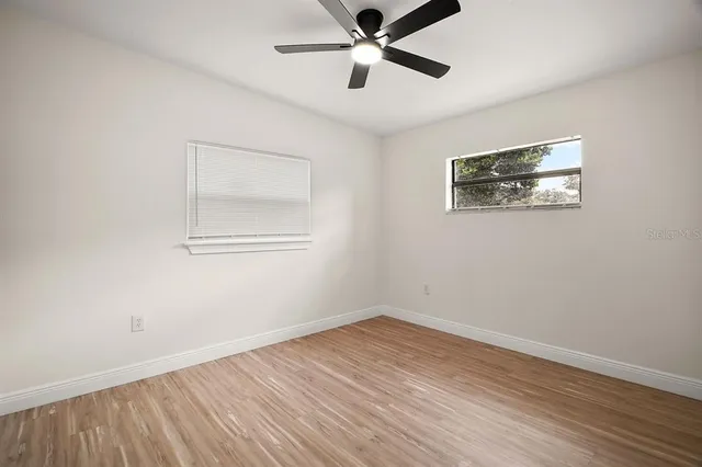a view of empty room with wooden floor and fan