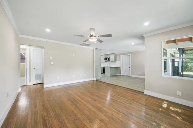 a view of an empty room with a window and wooden floor