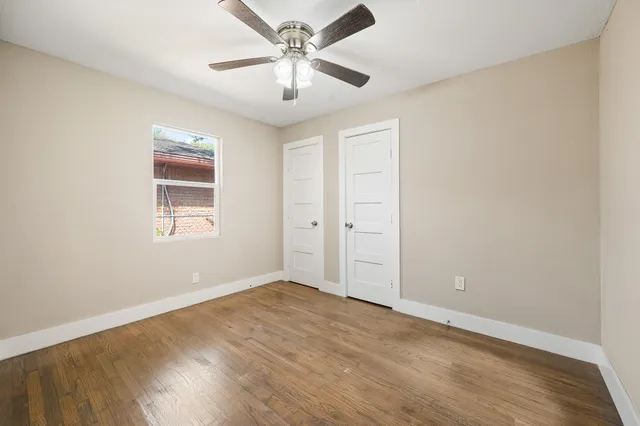 an empty room with wooden floor and ceiling fan