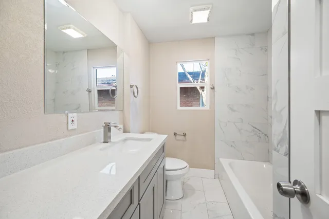 a bathroom with a sink a toilet a mirror and shower
