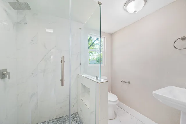 a bathroom with a granite countertop shower a toilet and a sink