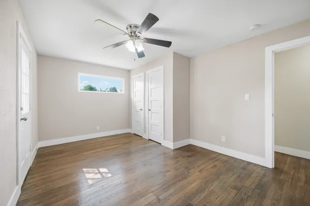 an empty room with wooden floor and chandelier fan