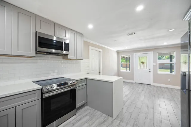 a kitchen with stainless steel appliances a stove microwave and sink