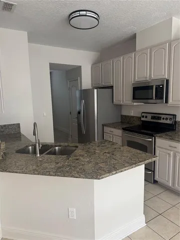 a kitchen with kitchen island granite countertop a sink a stove top oven a refrigerator and a counter space