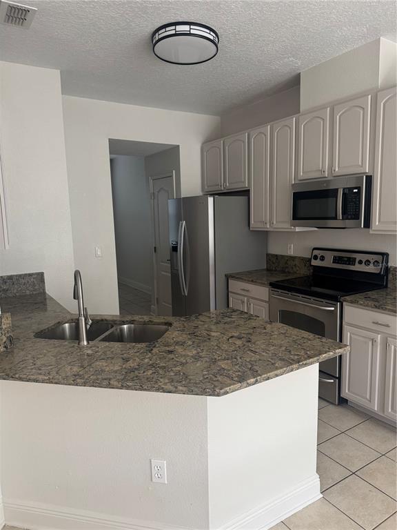 12976 Borland Street Windermere, FL 34786 - Photo 4 of 15 a kitchen with kitchen island granite countertop a sink a stove top oven a refrigerator and a counter space