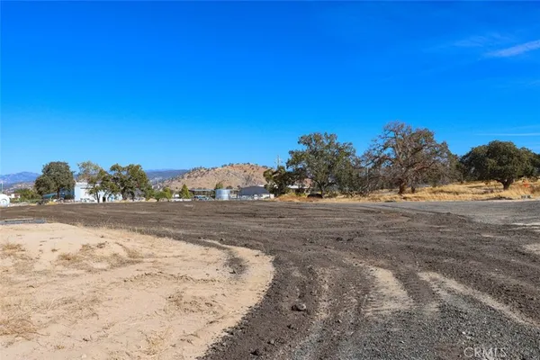 a view of dirt yard with mountain and trees around