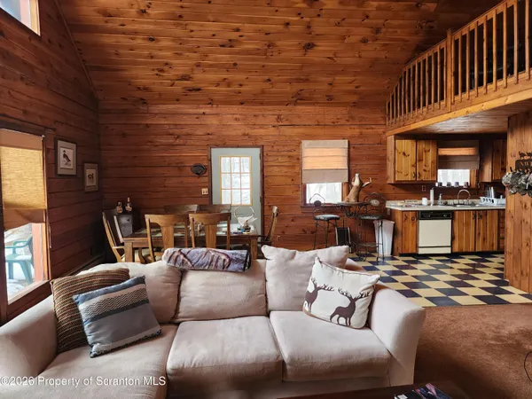 a living room with furniture wooden floor and a kitchen view