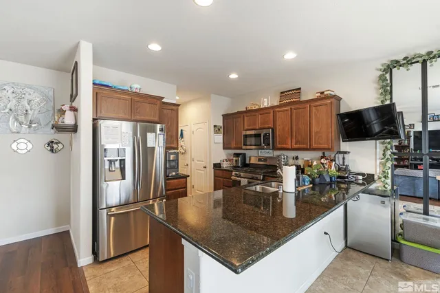 a kitchen with stainless steel appliances granite countertop a refrigerator a stove a microwave a sink and a refrigerator