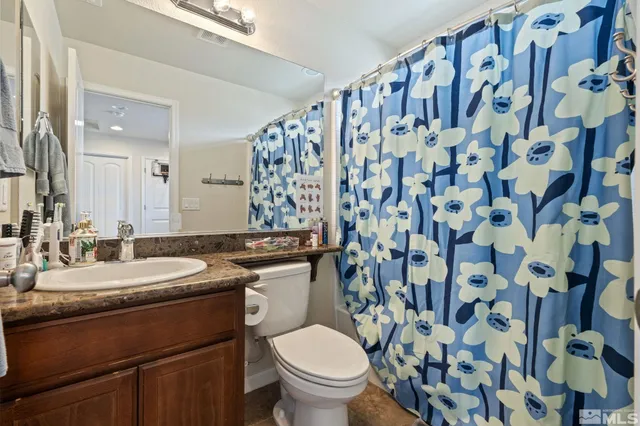 a bathroom with a granite countertop sink a toilet and a mirror