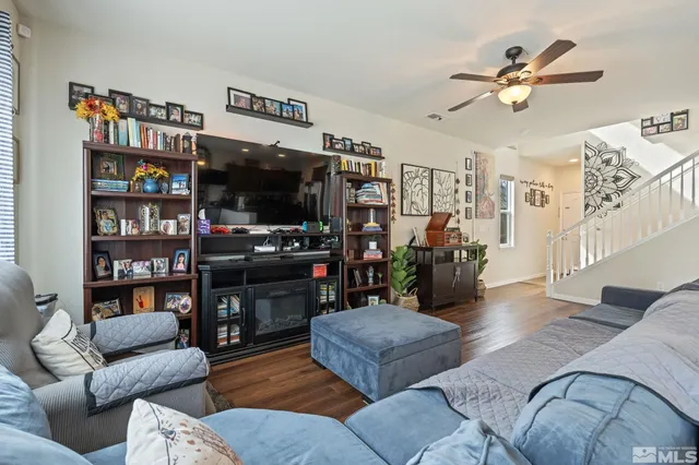 a living room with furniture a ceiling fan and a bookshelf