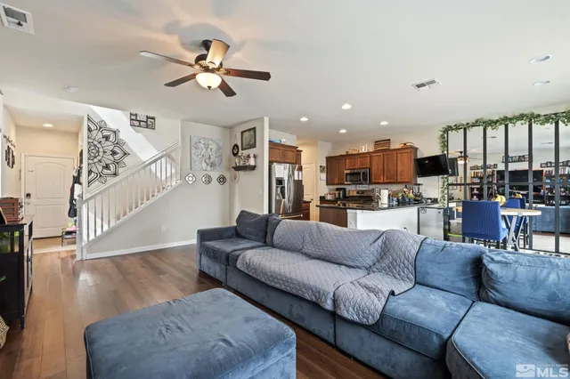 a living room with furniture kitchen view and a wooden floor