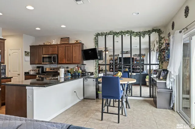 a kitchen with stainless steel appliances kitchen island granite countertop a stove top oven a sink a dining table and chairs