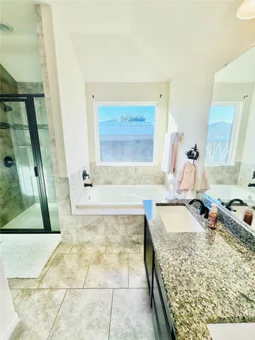 a spacious bathroom with a granite countertop sink and a bathtub